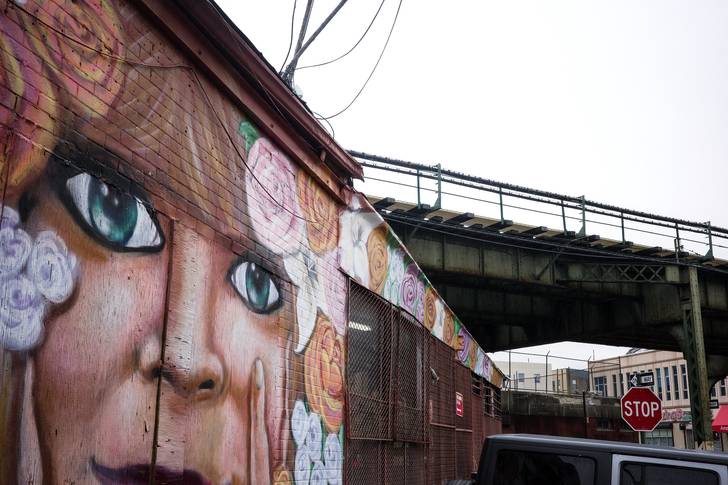 a mural of eyes next to elevated train tracks